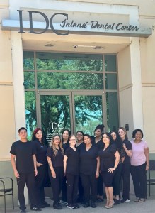 A group of dental professionals is standing outside the entrance of 