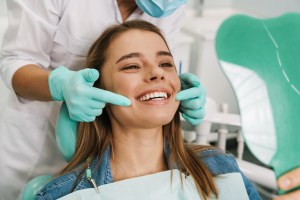 woman smiling in dental chair while dentist holds hands close to her mouth